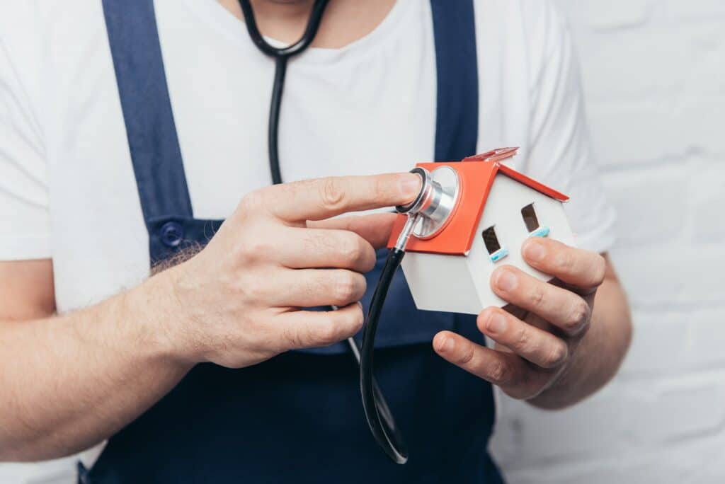 homme pose un stéthoscope sur une maison miniature. Concept diagnostique immobilier 