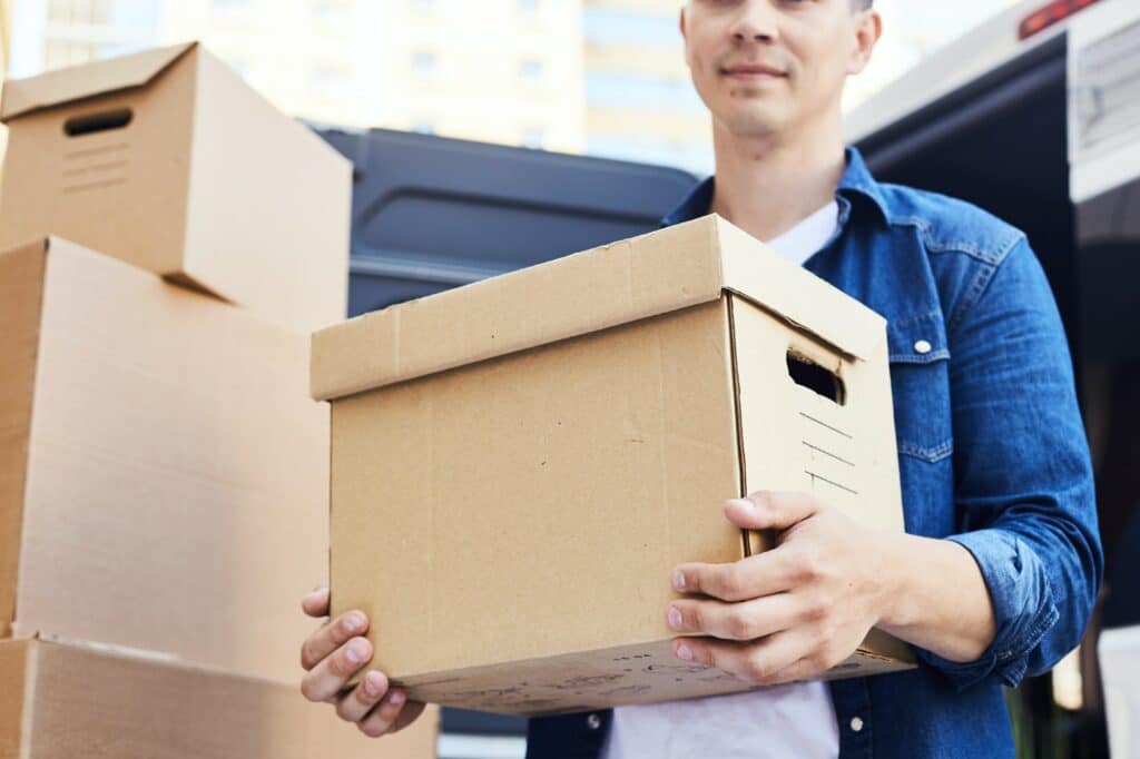 jeune colocataire déménage avec un carton dans les mains