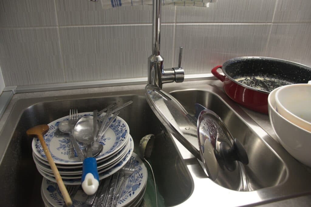 évier plein de vaisselle à cause d'une mauvaise répartition des tâches ménagères entre colocataires