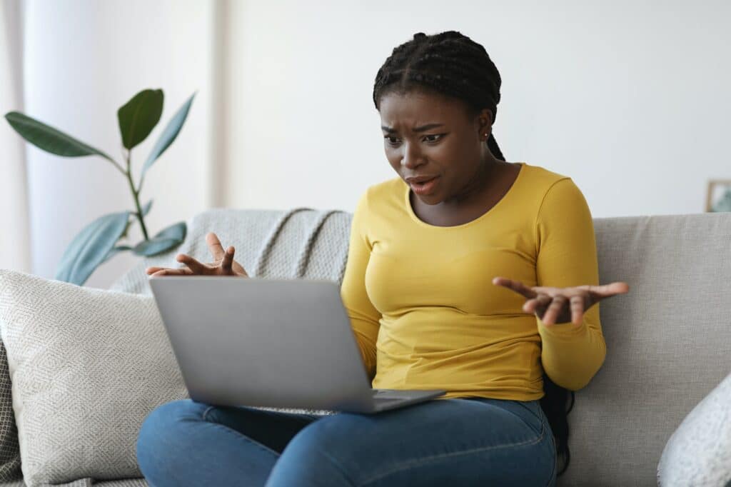 femme choquée devant son ordinateur après une arnaque