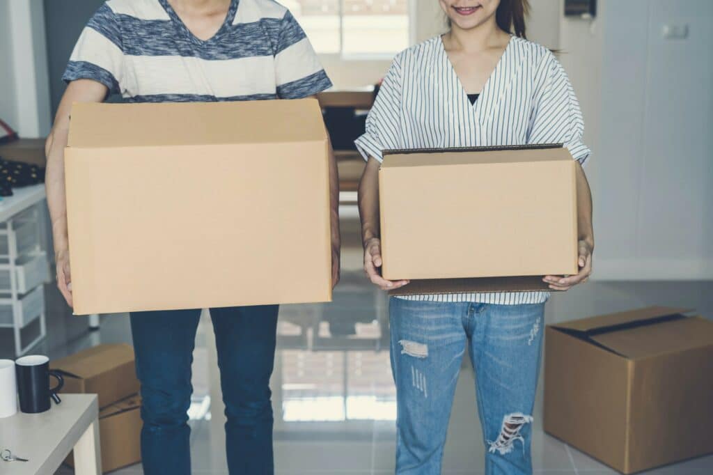 deux colocataires portent des cartons de déménagement