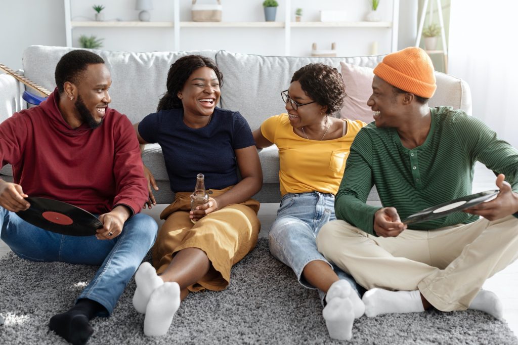 Happy african american friends sitting on floor in living room